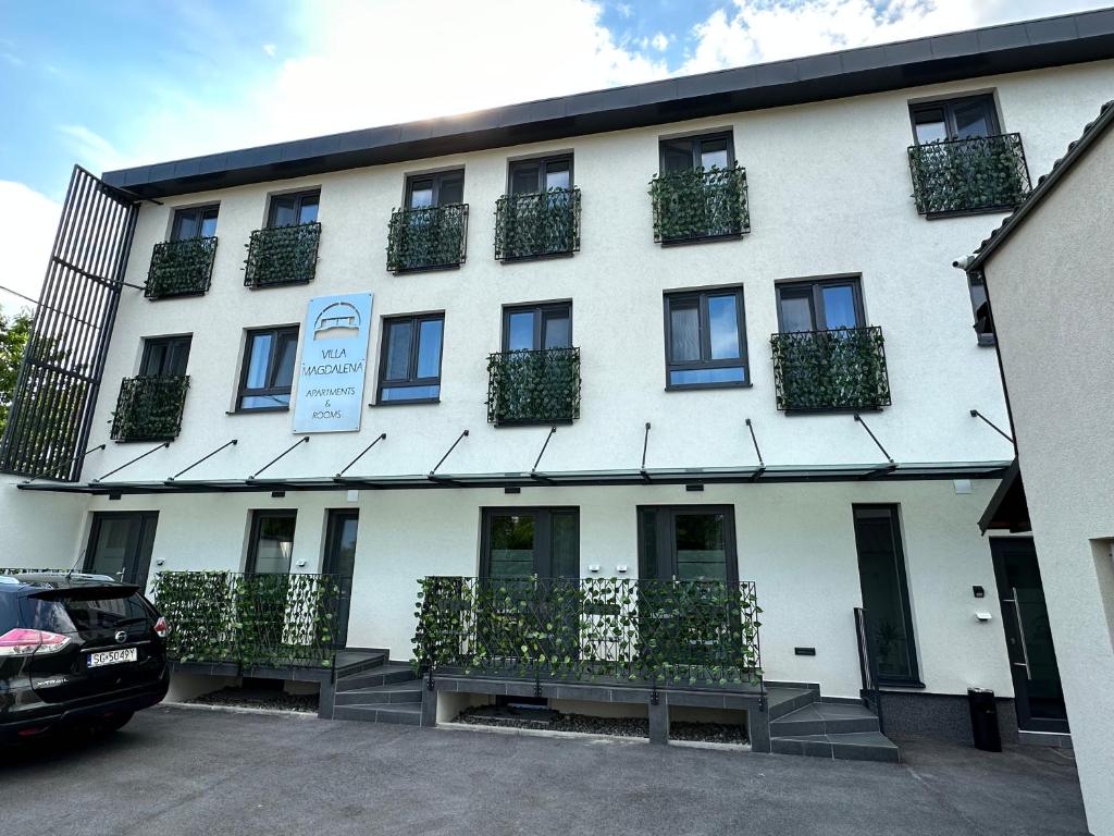 ein weißes Gebäude mit nebenstehenden Pflanzen in der Unterkunft Villa Magdalena apartments & rooms in Maribor