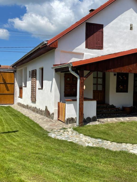 Casa blanca con techo rojo y patio en La Novaci Porumbacu de Sus 270, en Porumbacu de Sus