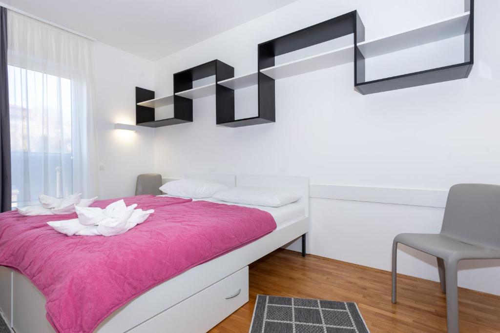 um quarto com uma cama com um cobertor rosa em Rooms Kampus em Split