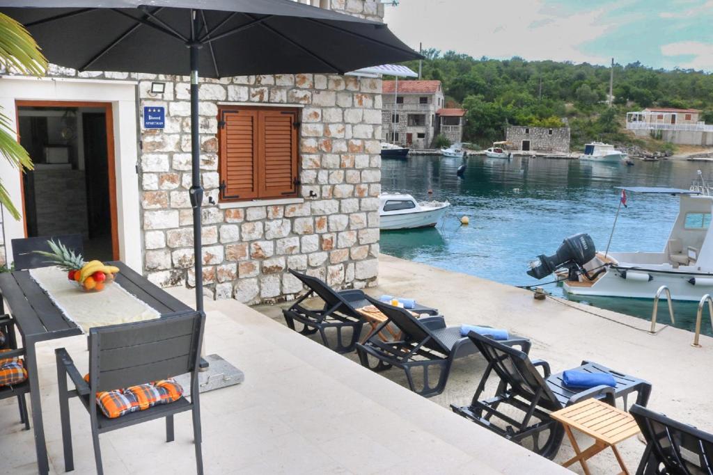 a patio with a table and chairs and an umbrella at Apartments Melany in Slano