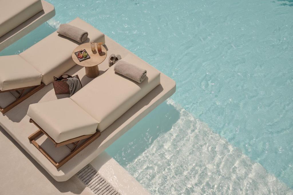 a pool with chairs and a table and the water at Yi Hotel Mykonos in Elia Beach