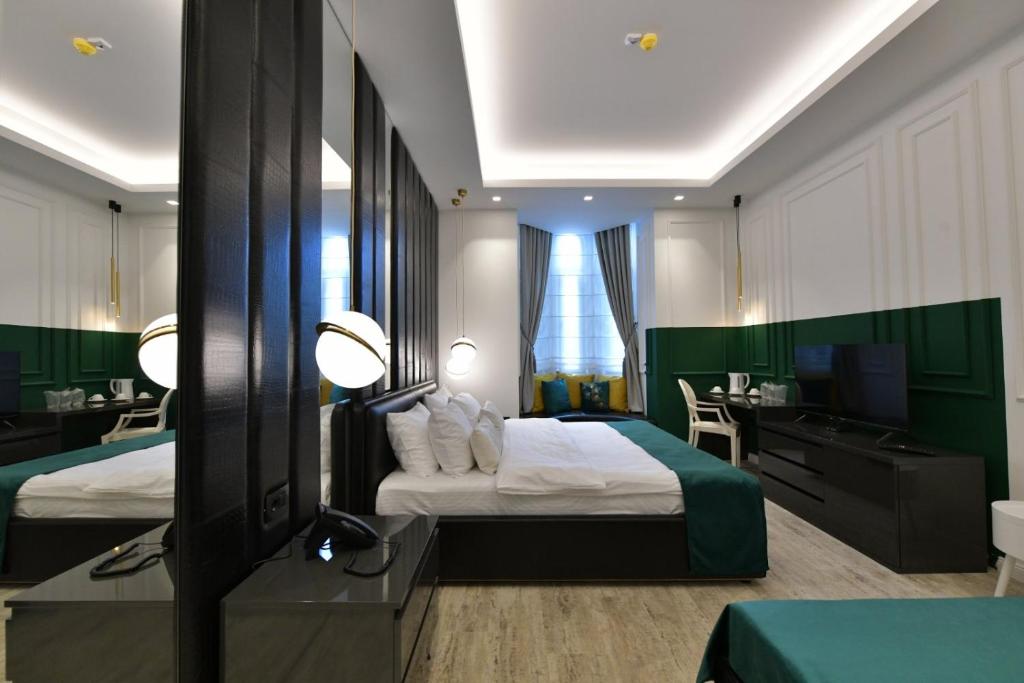 um quarto de hotel com duas camas e uma secretária e uma televisão em Royal Wellness and Spa em Ruma