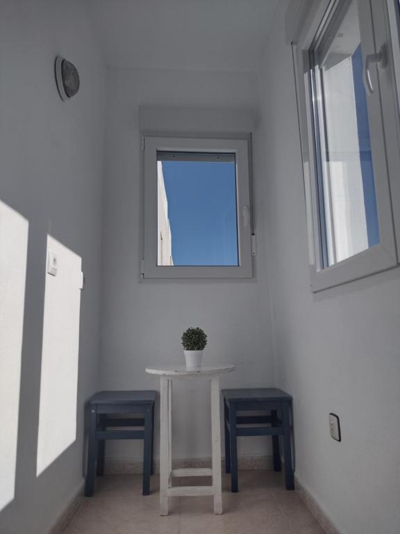 a table and two stools in a room with a window at Apartamento playa de los Lances in Tarifa