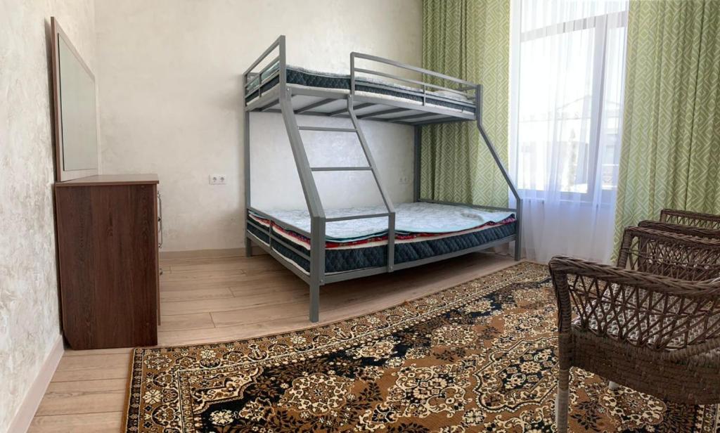 una camera con 2 letti a castello e una sedia di Коттедж Palm beach a Chok-Tal