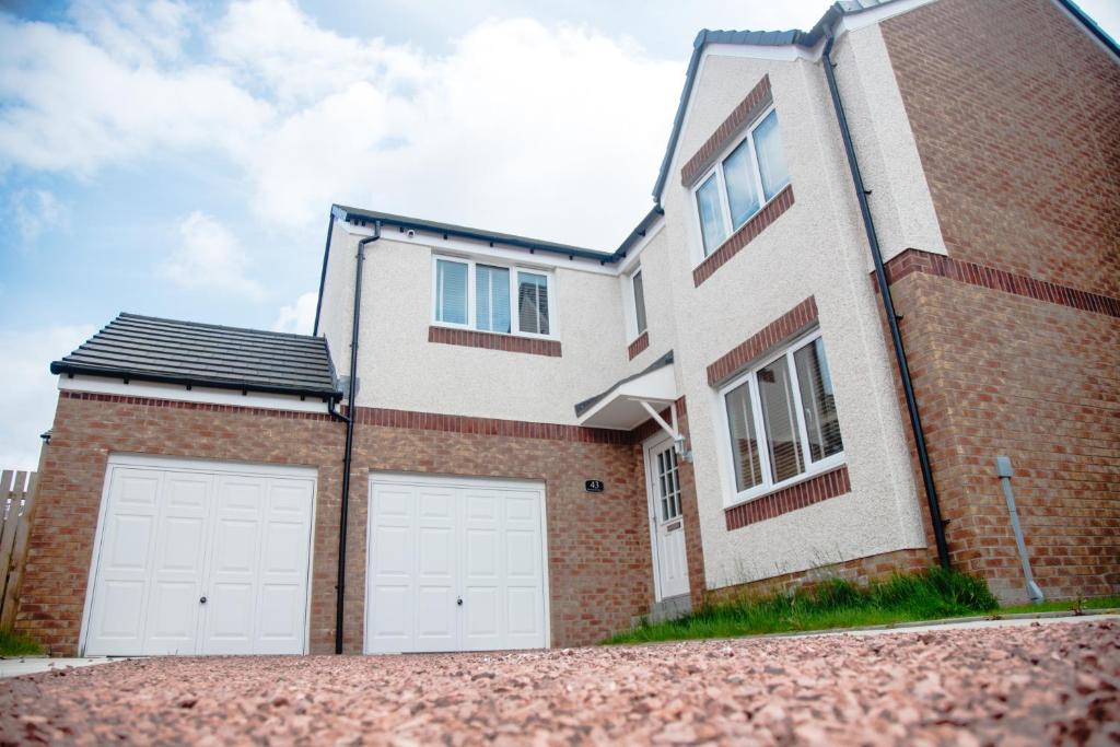 a brick house with two white garage doors at Beautiful 5 Bedroom House in Glasgow in Cambuslang