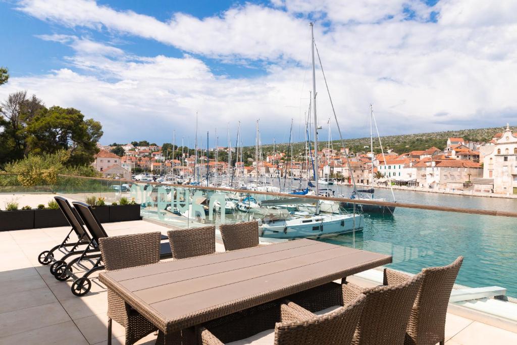 a wooden table and chairs on a balcony with a marina at Apartment ACI Marina MILNA Brač in Milna