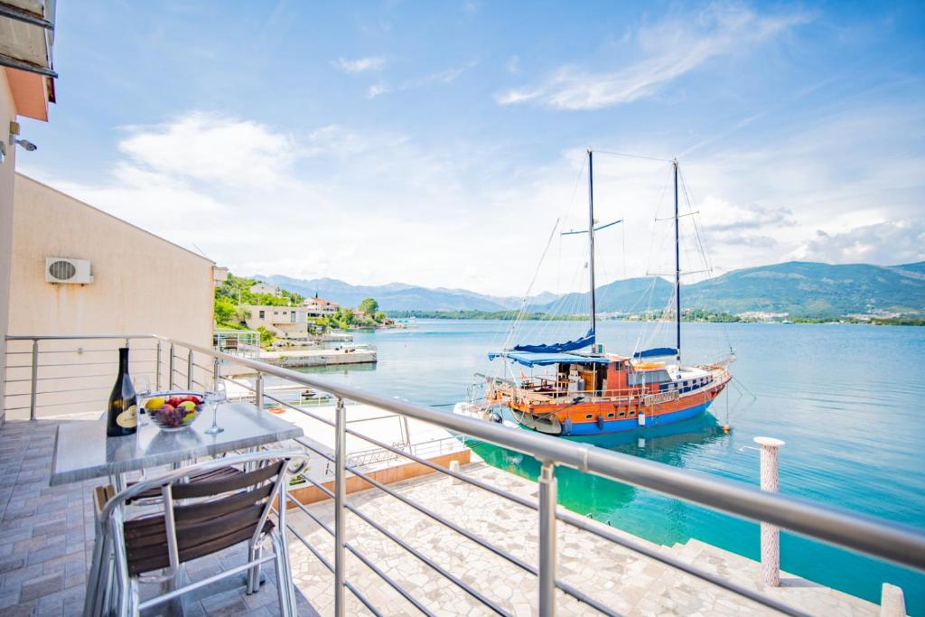 a boat sitting on the water next to a balcony at Apartmani Bonaca in Tivat