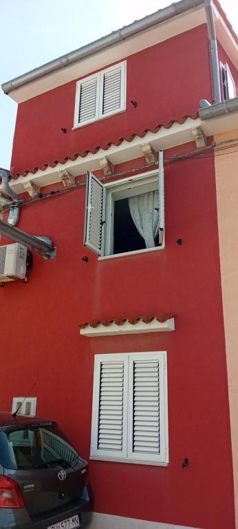 een rood gebouw met een raam met een wit gordijn bij Apartment Antonio in Pula