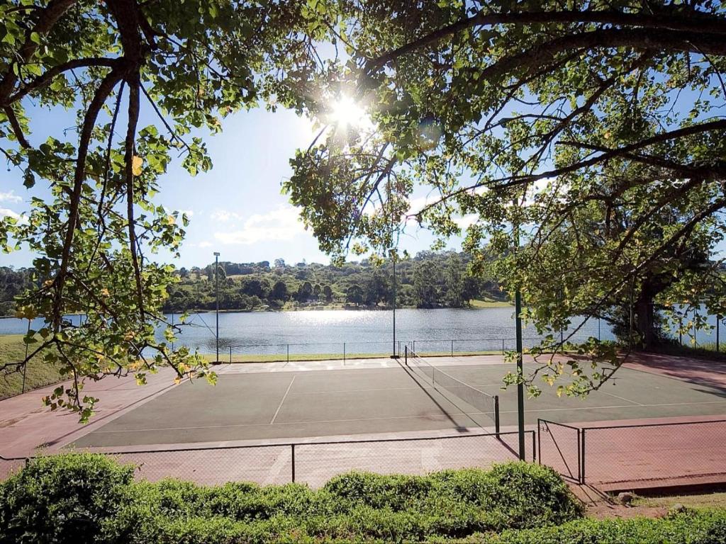 a tennis court next to a body of water at Blue Zone Leisure at Pine Lake Inn Resort in White River