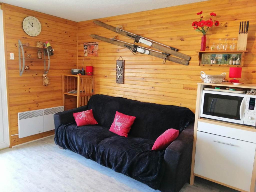 ein Wohnzimmer mit einem schwarzen Sofa und einer Mikrowelle in der Unterkunft Appartement Les Adrets-Prapoutel, 2 pièces, 5 personnes - FR-1-557-57 in Les Adrets
