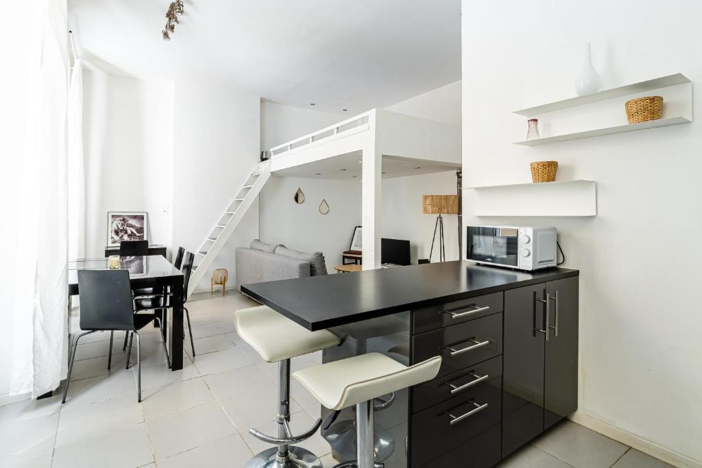 une cuisine et une salle à manger avec un comptoir noir et des chaises dans l'établissement Chevalier Paul-Charmant-Mezzanine - 4 personnes, à Marseille