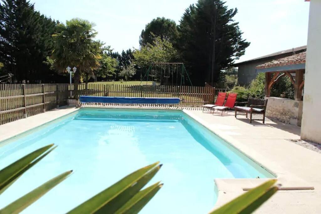 - une grande piscine bleue avec 2 chaises dans la cour dans l'établissement Gite La Grange du Pech, à Lacour