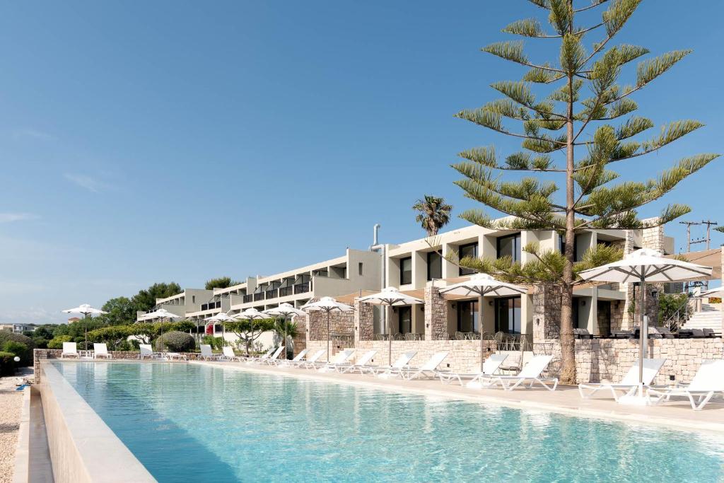 a resort pool with chairs and a palm tree at Achilles Hill Hotel in Methoni