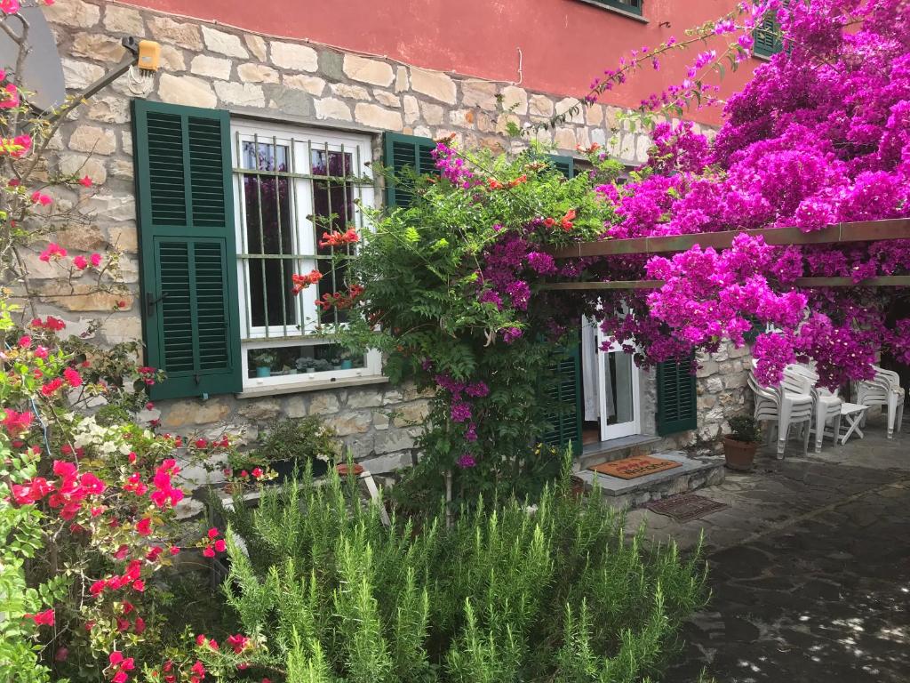 um edifício com flores e uma janela com persianas verdes em [Portofino] Appartamento in Villa vista mare em Lavagna