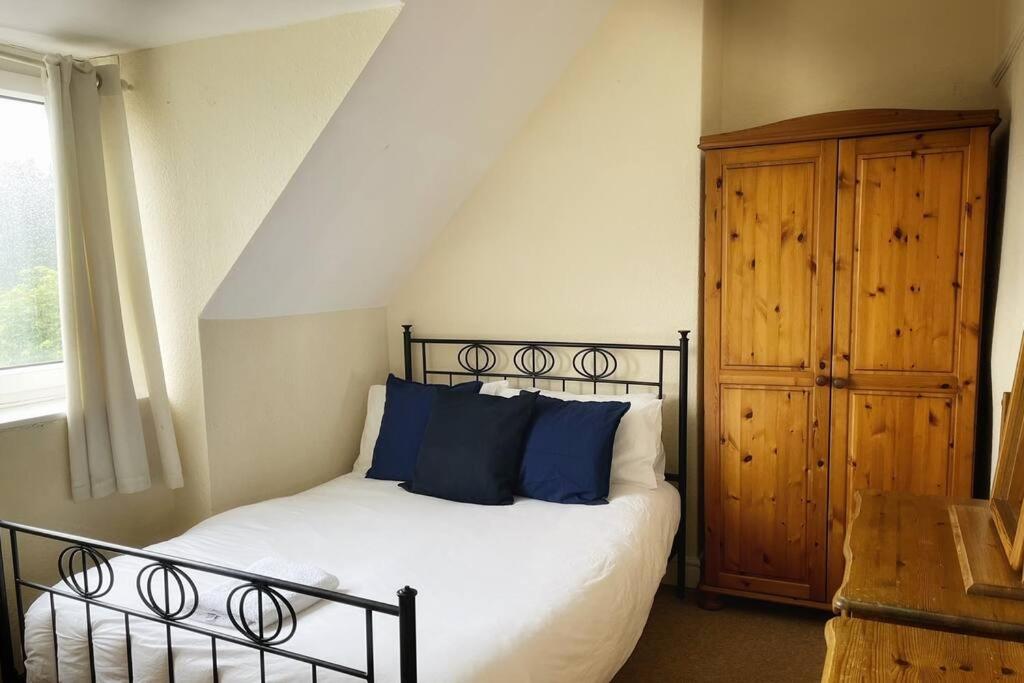 a bedroom with a bed with blue pillows and a wooden cabinet at Views over the Peak District Apartment with WIFI in Sheffield