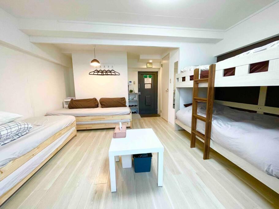 大阪市にあるSUNRISE APT 新大阪駅から徒歩5分観光都市へのアクセス抜群Simply Guest Room Shin-Osakaの二段ベッド2台とテーブルが備わる客室です。
