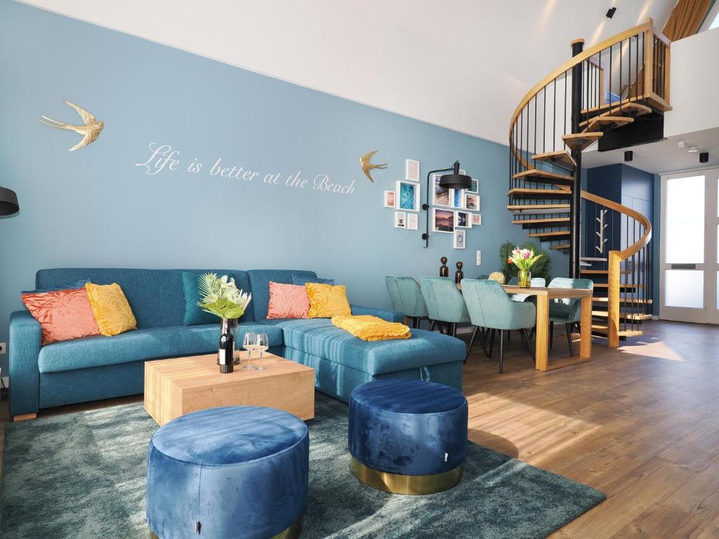 a living room with a blue couch and a staircase at Seebrücke Heringsdorf - Appartement mit 1 Schlafzimmer und Terrasse S18 in Heringsdorf
