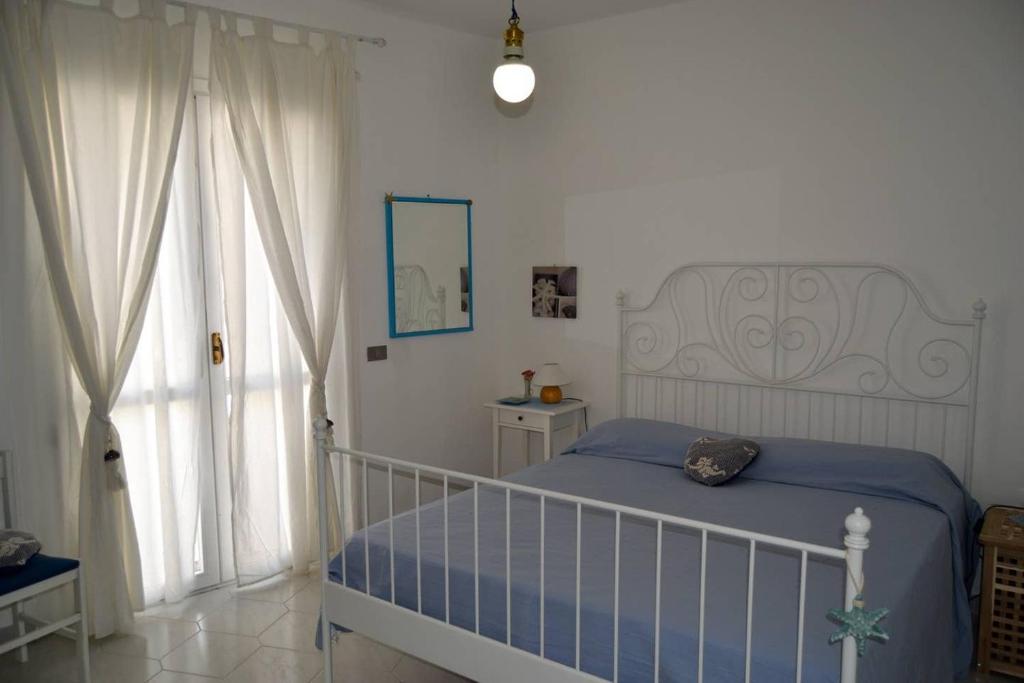um quarto branco com uma cama e uma janela em Casa Clarissa em Marina di Casalvelino