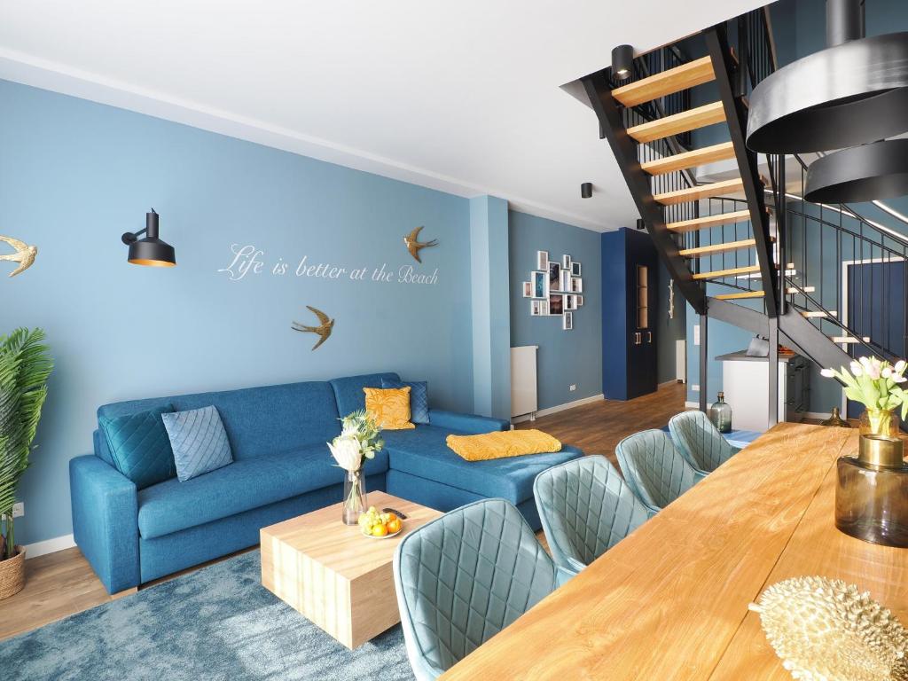 ein Wohnzimmer mit einem blauen Sofa und einem Holztisch in der Unterkunft Seebrücke Heringsdorf - Appartement mit 2 Schlafzimmern S20 in Heringsdorf