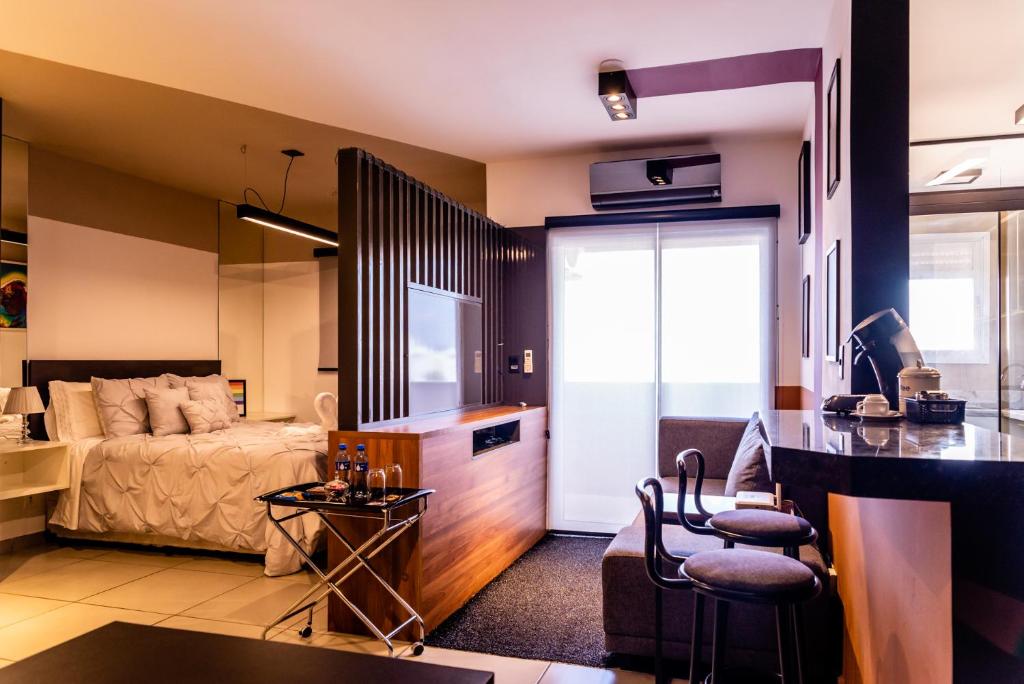 a bedroom with a bed and a living room at Loft Campolim in Sorocaba