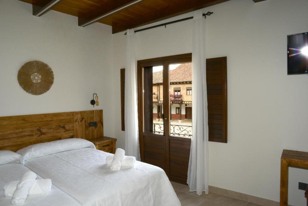 ein Schlafzimmer mit einem Bett und einer Glasschiebetür in der Unterkunft El Corazón de la Villa in Saldaña