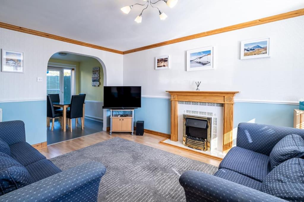 a living room with two blue chairs and a fireplace at Seaside Home with Sea Views in Balmedie