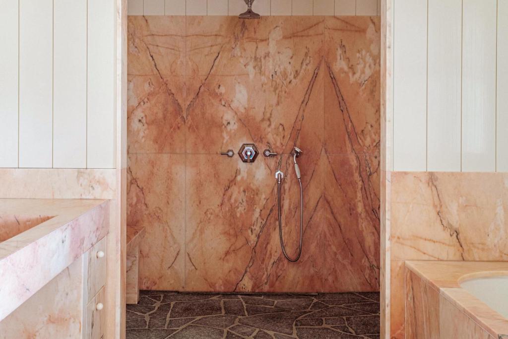 a shower in a bathroom with a brown wall at Cap d'Antibes Beach Hotel in Juan-les-Pins