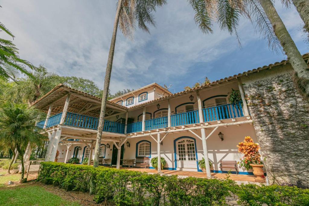 a large house with blue balconies and palm trees at Fazenda Alvorada in Sorocaba