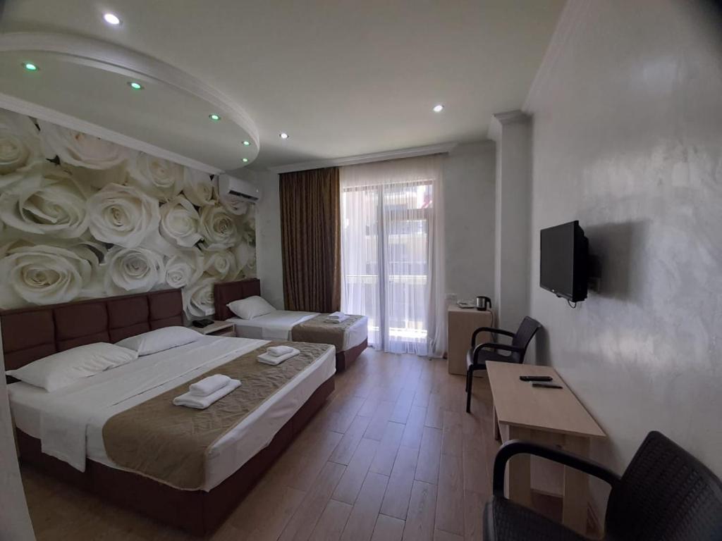 una habitación de hotel con una cama con rosas en la pared en Hotel Royal Palace, en Batumi