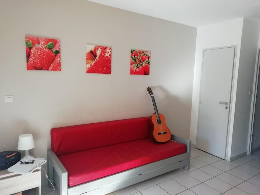 un banc rouge avec une guitare sur un mur dans l'établissement Les pieds dans l'eau !, à Cerbère
