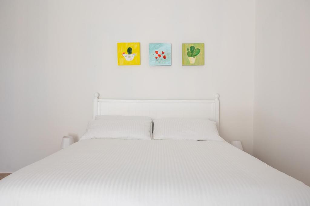 ein weißes Bett mit drei Bildern an der Wand in der Unterkunft Masseria Spiga in Gravina in Puglia