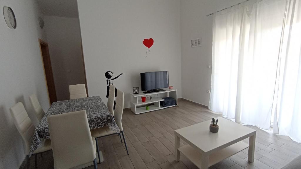 un salon avec une table et une télévision dans l'établissement Apartmani URANIJA, à Sveti Filip i Jakov