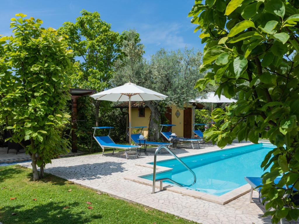 a pool with chairs and umbrellas next to a house at Holiday Home Olive Grove Sabina by Interhome in Canneto