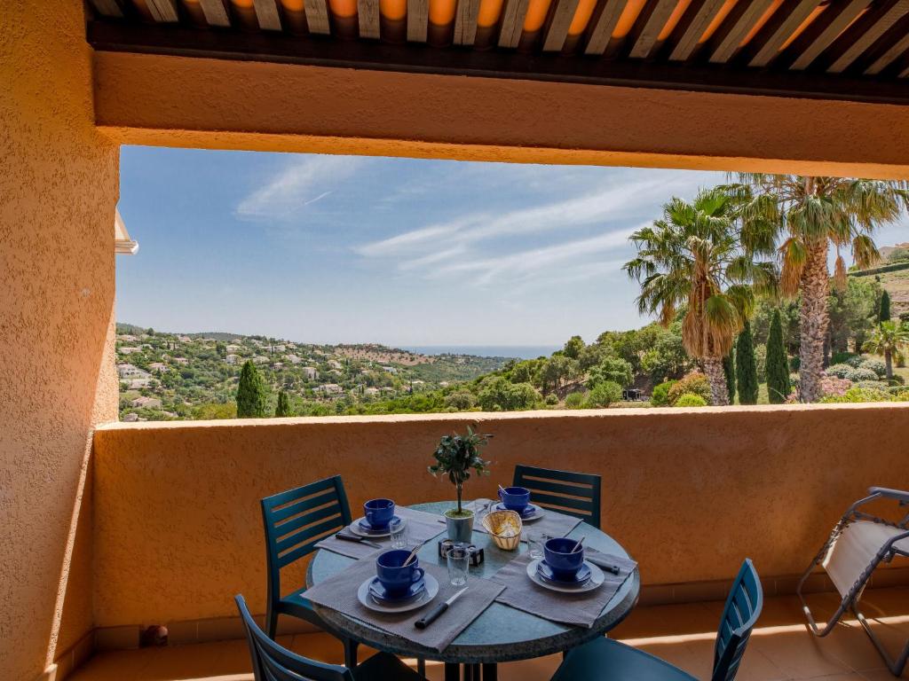 a table and chairs on a balcony with a view at Apartment Les Hauts des Issambres-1 by Interhome in La Garonnette-Plage