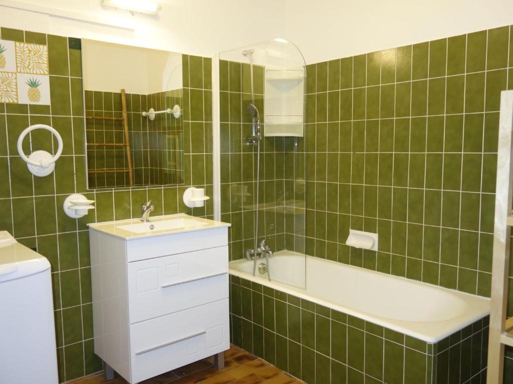 a green tiled bathroom with a tub and a sink at Apartment Hameau la Madrague-22 by Interhome in La Madrague