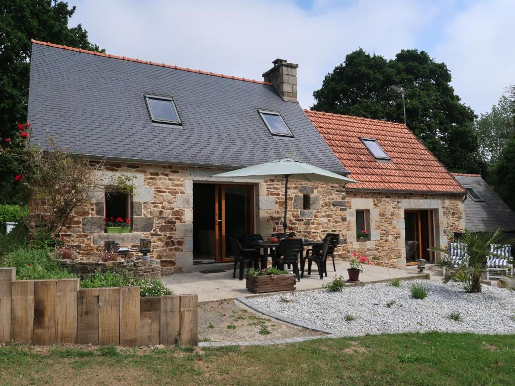 a stone house with a table and an umbrella at Holiday Home Entre Terre et Mer - PML102 by Interhome in Ploumilliau