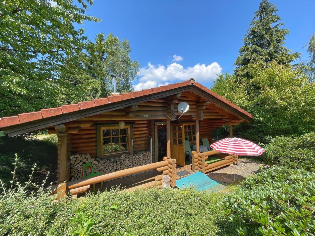 une petite cabane en rondins avec un parasol dans la cour dans l'établissement Chalet Birdieferienhaus by Interhome, à Leisel