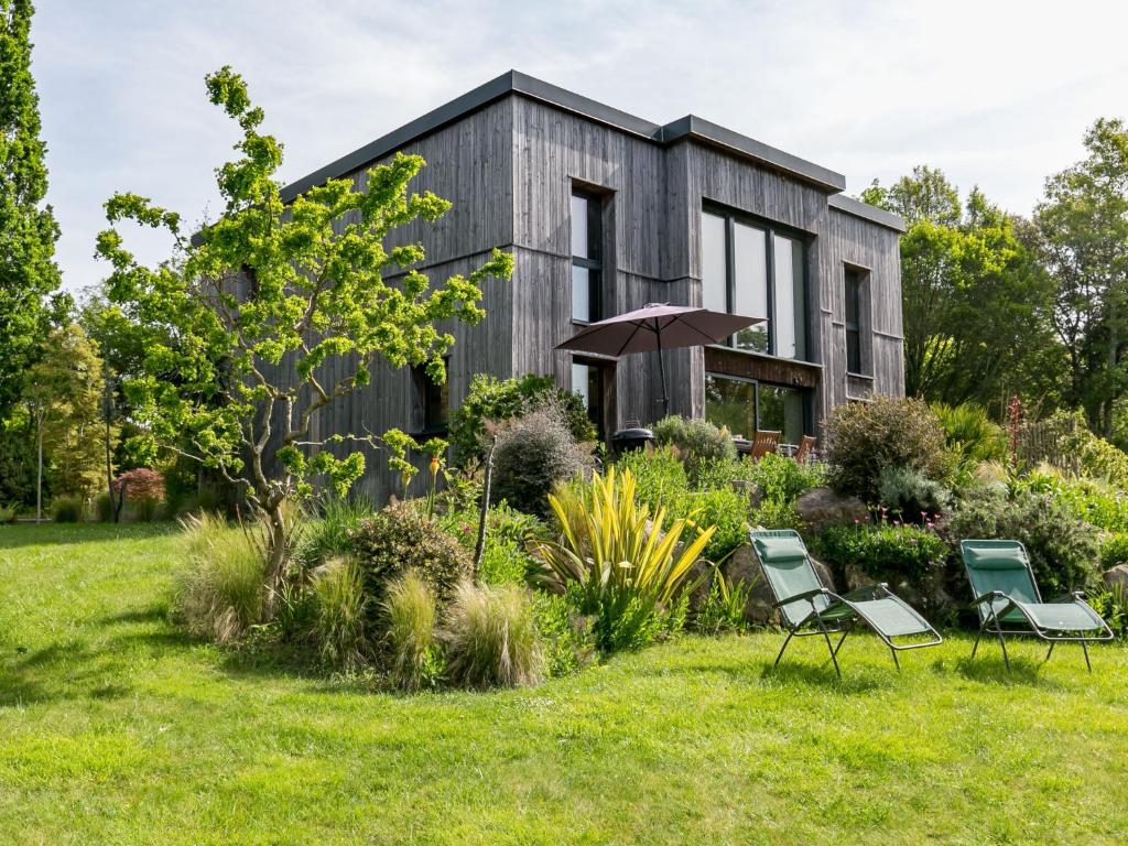 a house with a garden and two chairs in front of it at Chalet Ty Coat by Interhome in La Forêt-Fouesnant