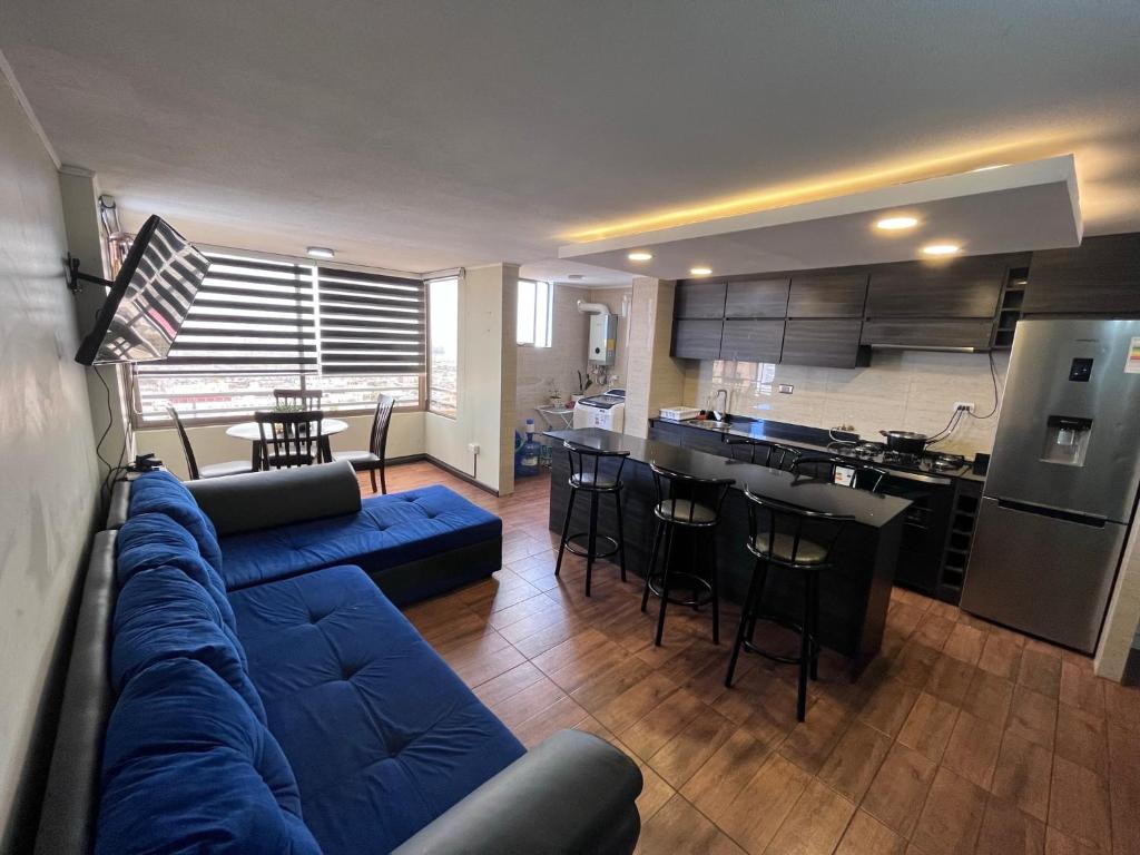 a living room with a blue couch and a kitchen at Elegante departamento in Iquique