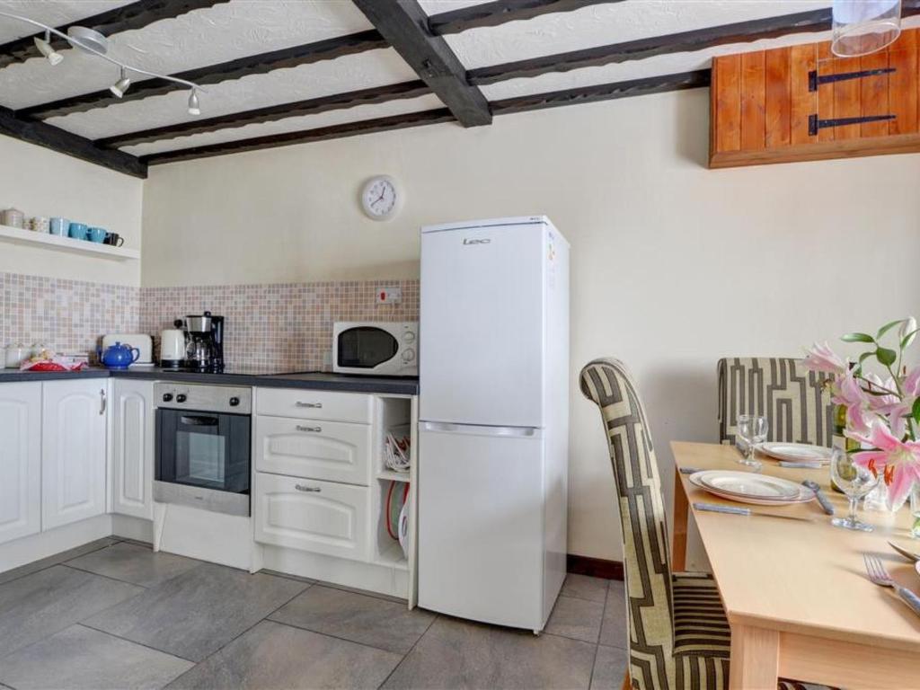 a kitchen with a white refrigerator and a table at Holiday Home Mill Court by Interhome in Swimbridge