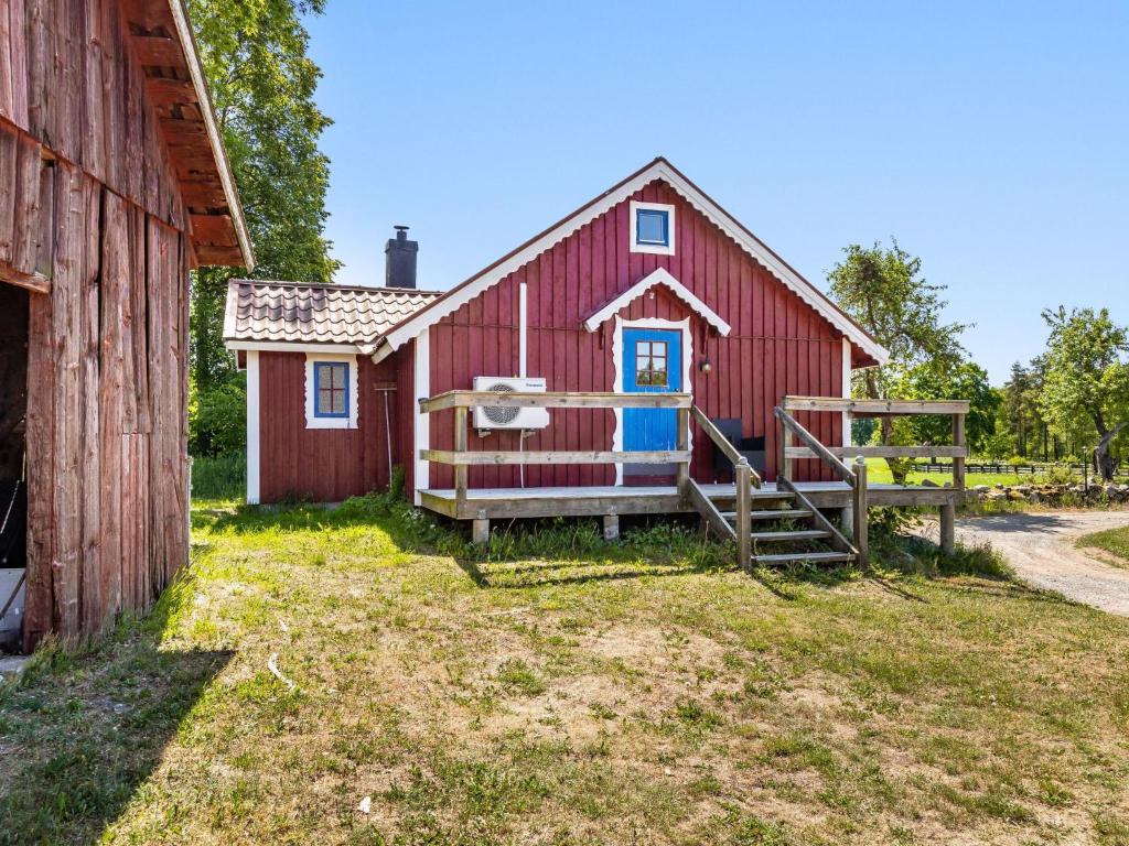 Kalvsvik的住宿－Holiday Home Skärvudde Torpet - SND083 by Interhome，红谷仓,有蓝色的门和栅栏