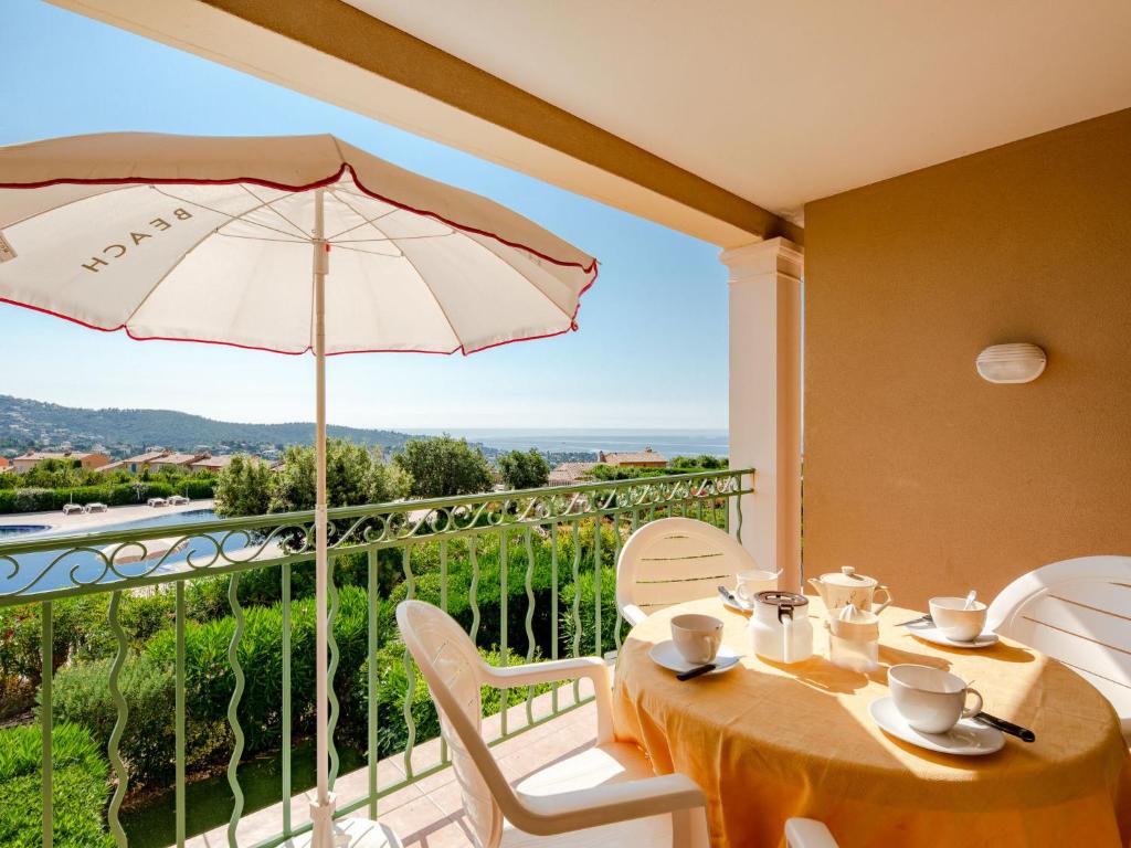 - une salle à manger avec une table et un parasol dans l'établissement Apartment Le Hameau des Issambres-5 by Interhome, aux Issambres