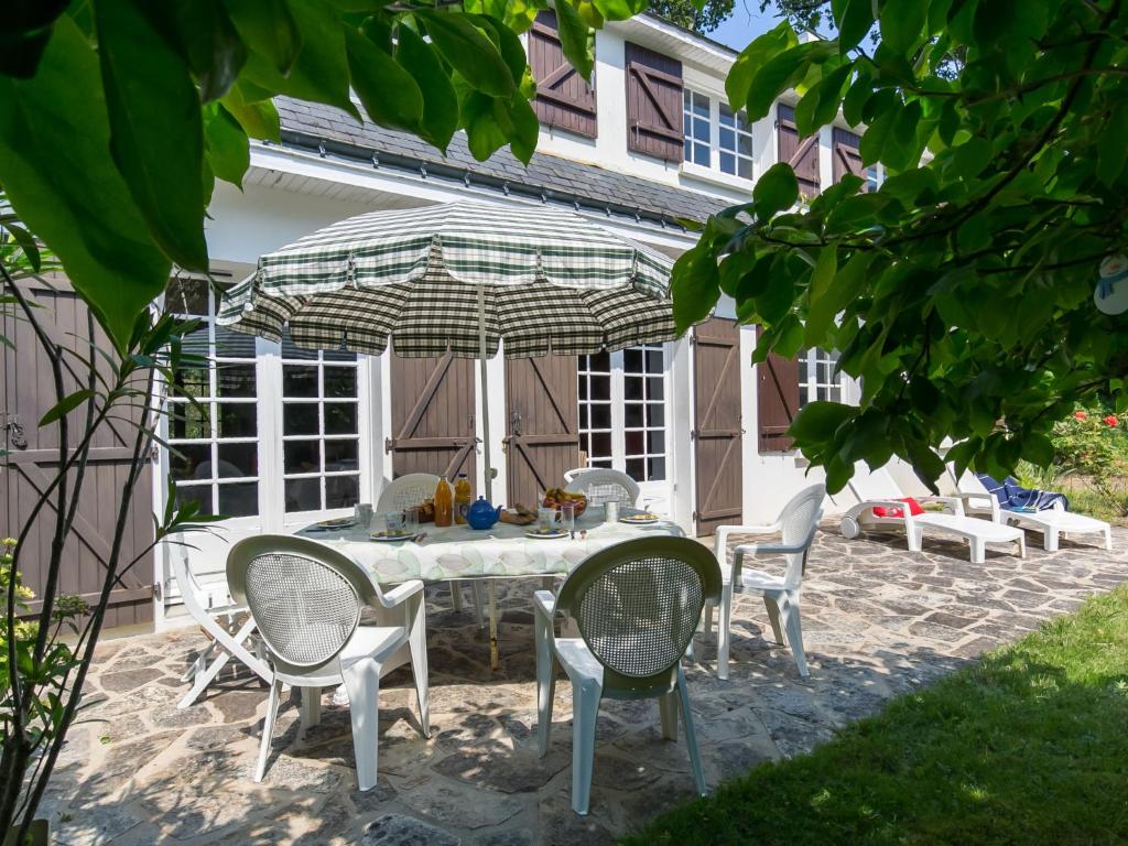 um pátio com uma mesa, cadeiras e um guarda-sol em Holiday Home Bellevue - MSR103 by Interhome em Moëlan-sur-Mer