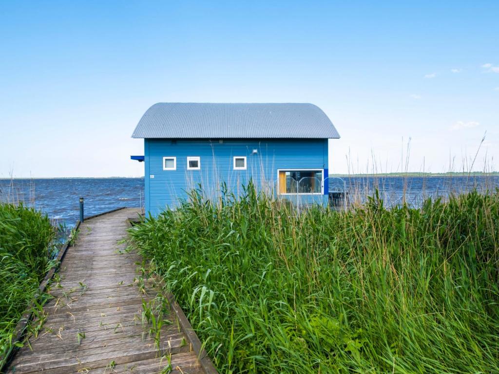 ein blaues Haus am Strand neben dem Wasser in der Unterkunft Holiday Home Jachthaven Oostmahorn by Interhome in Anjum