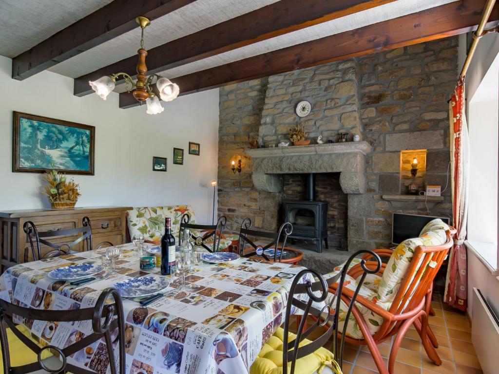 a dining room with a table and a stone fireplace at Holiday Home Blaue Hortensie - SZN100 by Interhome in Sizun