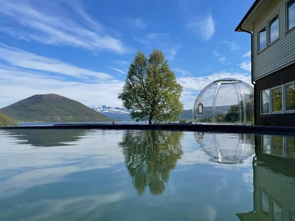 uma casa com uma cúpula de vidro ao lado de uma massa de água em Tjeldøya Slott em Hov