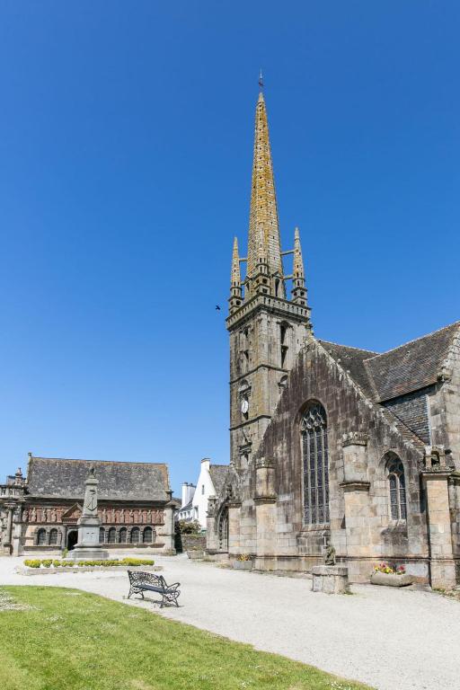 a church with a tower and a bench in front of it at Holiday Home Blaue Hortensie - SZN100 by Interhome in Sizun