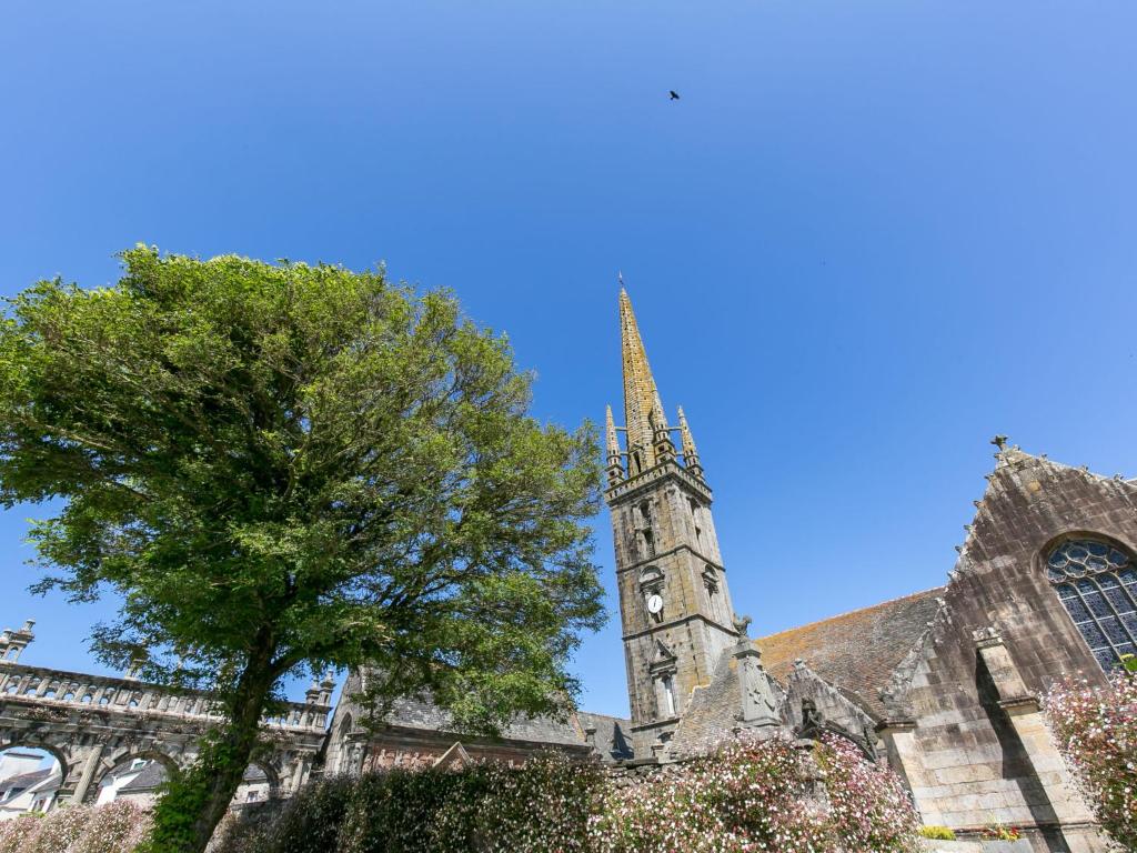 a church with a steeple and a clock tower at Holiday Home Blaue Hortensie - SZN100 by Interhome in Sizun