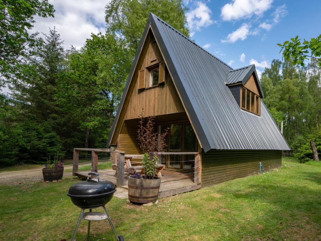a log cabin with a grill in front of it at Chalet Rowan Cottage by Interhome in Inverness