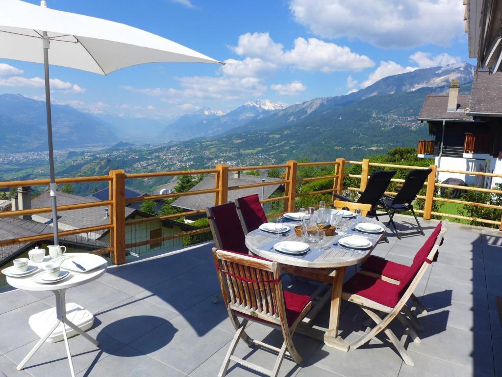 a table with chairs and an umbrella on a balcony at Chalet La Délège by Interhome in Crans-Montana